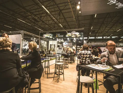 B2B trade show attendees connecting over coffee in a casual booth setting.